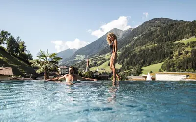 a man and a woman standing in a swimming pool at Stroblhof Active Family Spa Resort in San Leonardo in Passiria