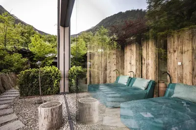 a patio with a couch and a wooden fence at Stroblhof Active Family Spa Resort in San Leonardo in Passiria