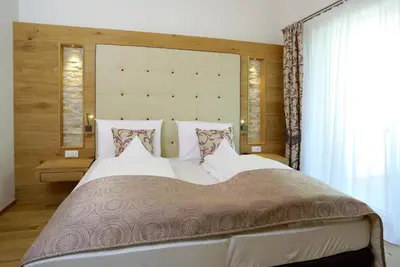 a bedroom with a large bed with a large headboard at Stroblhof Active Family Spa Resort in San Leonardo in Passiria