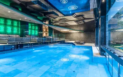 a swimming pool in a building with a lit up swimming pool at Stroblhof Active Family Spa Resort in San Leonardo in Passiria
