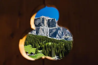 a view of a mountain through a hole in a door at Wellness Hotel Lupo Bianco in Canazei
