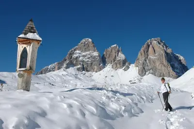 a man on skis in the snow next to a church at Wellness Hotel Lupo Bianco in Canazei