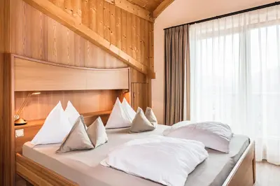 a bedroom with a large bed with white pillows at Hotel Weingarten in Appiano sulla Strada del Vino