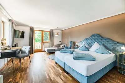a bedroom with a large bed and a living room at Hotel Weingarten in Appiano sulla Strada del Vino