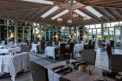 a restaurant with white tables and chairs and windows at Hotel Weingarten in Appiano sulla Strada del Vino