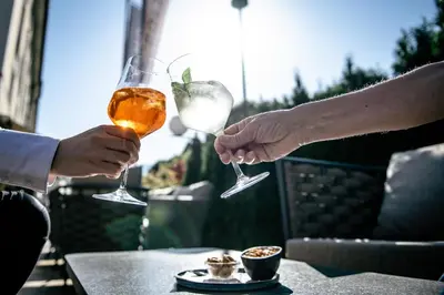 two people holding wine glasses on a table at HOTEL POST alpine cityflair in Brunico