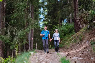 a man and a woman walking on a dirt trail at Naturhotel Miraval in Perca