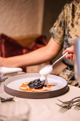 a woman laying in bed eating a piece of food at Wellnesshotel Erica in Nova Ponente