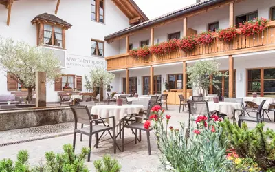 a restaurant with tables and chairs in front of a building at Apartment Lodge Gasserhof in Bressanone