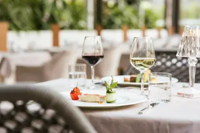 a table with two glasses of wine and a plate of food at Hotel Wiesenhof in Lagundo