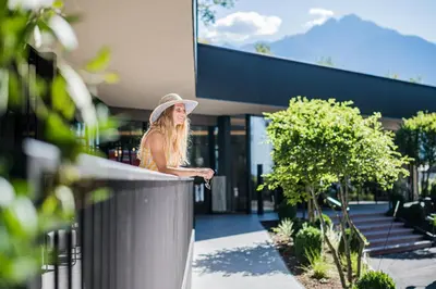 a woman in a hat standing in front of a building at Hotel Wiesenhof in Lagundo