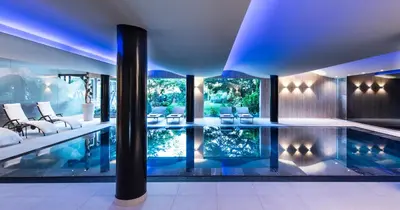a swimming pool in a house with blue lighting at Hotel Wiesenhof in Lagundo