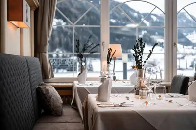 a restaurant with two tables and red chairs at Alpenheim Charming & Spa Hotel in Ortisei