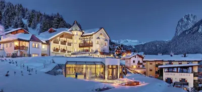 a woman standing in front of a body of water at Alpenheim Charming & Spa Hotel in Ortisei