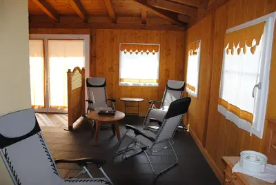 a room with chairs and a table and windows at Dolasilla Park Hotel in Vigo di Fassa
