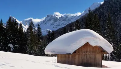 a small wooden house covered in snow on a mountain at Dolasilla Park Hotel in Vigo di Fassa
