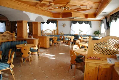 a restaurant with wooden tables and chairs and windows at Dolasilla Park Hotel in Vigo di Fassa