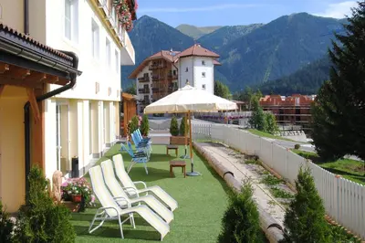 a group of lawn chairs and an umbrella on a building at Dolasilla Park Hotel in Vigo di Fassa