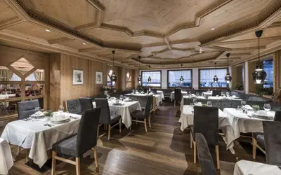 a restaurant with white tables and chairs and wooden ceilings at Ferien & Wellnesshotel Windschar in Brunico