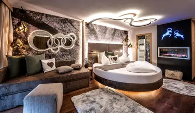 a bedroom with a large bed and a couch at ABINEA Dolomiti Romantic SPA in Castelrotto