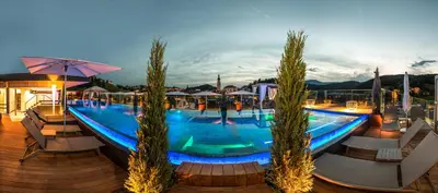 a swimming pool with trees and umbrellas at night at ABINEA Dolomiti Romantic SPA in Castelrotto