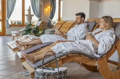 a man and a woman sitting in a rocking chair with their cell phones at Miraval Hotel in Coredo