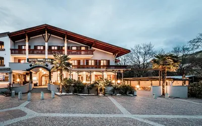 a large building with palm trees in front of it at Hotel Clara in Bressanone