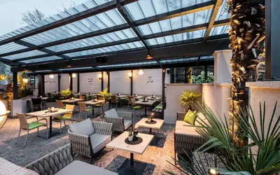 an outdoor restaurant with tables and chairs and windows at Hotel Clara in Bressanone