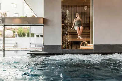 a woman sitting on the stairs next to a swimming pool at Hotel Clara in Bressanone