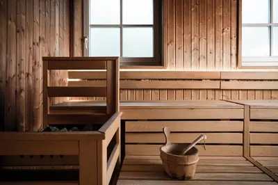 a sauna with a bucket and a chair and windows at Hotel Clara in Bressanone