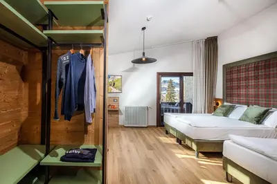 a bedroom with a bed and a couch and a table at Hotel Nigritella in Selva di Cadore