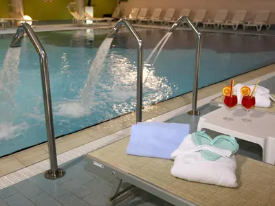 a pool with a table with towels and glasses on it at Hotel Nigritella in Selva di Cadore