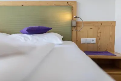 a bed with a purple pillow next to a table at Mounthotel Niggl in Nova Levante