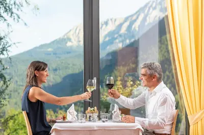 a man and woman sitting at a table with wine glasses at Mounthotel Niggl in Nova Levante