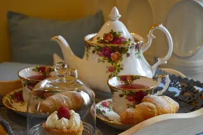 a table topped with cups and pastries and a tea pot at Hotel Garnì Carpe Diem in Vigo di Fassa
