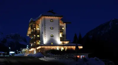a large building with lights on it at night at Hotel Garnì Carpe Diem in Vigo di Fassa