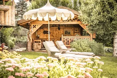 a couple of chairs and an umbrella in a garden at Hotel Luna Mondschein in Ortisei