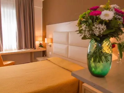 a vase of flowers sitting on a table in a bedroom at Hotel Regina in Bolzano