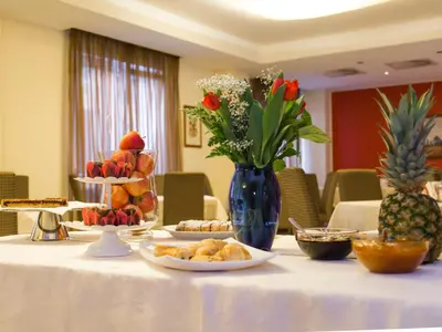 a table topped with plates of food and a vase of flowers at Hotel Regina in Bolzano