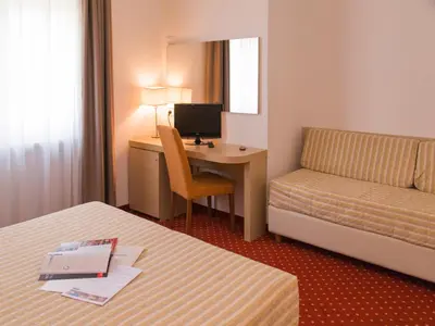 a hotel room with a bed and a desk with a computer at Hotel Regina in Bolzano