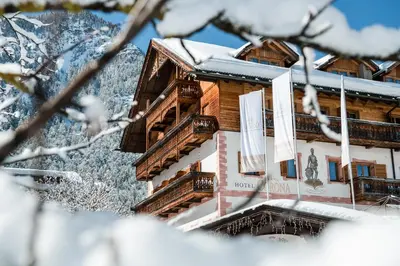 a building with balconies and snow covered trees at Kristallhotel Corona-Krone in San Vigilio Di Marebbe