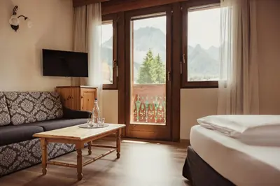 a hotel room with a bed and a couch and a table at Kristallhotel Corona-Krone in San Vigilio Di Marebbe