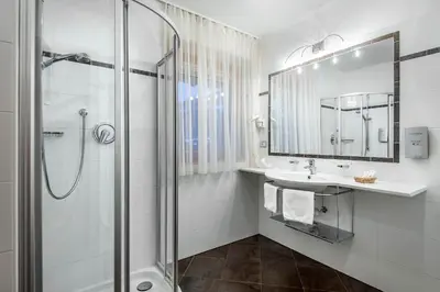 a white bathroom with a shower and a sink at Kristallhotel Corona-Krone in San Vigilio Di Marebbe