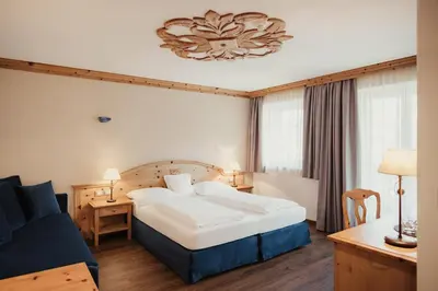 a hotel room with a bed and a couch at Kristallhotel Corona-Krone in San Vigilio Di Marebbe