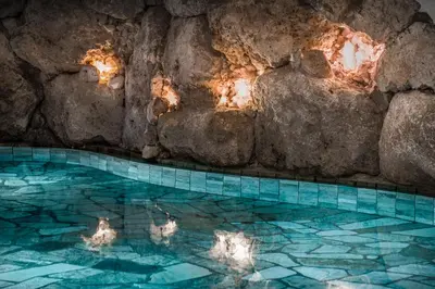a swimming pool in a cave with a rock wall at Kristallhotel Corona-Krone in San Vigilio Di Marebbe