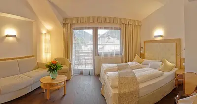 a hotel room with a bed and a couch and a window at Hotel Leitner in Mühlbach