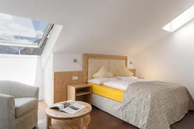 a bedroom with a bed and a couch and a chair at Hotel Leitner in Mühlbach