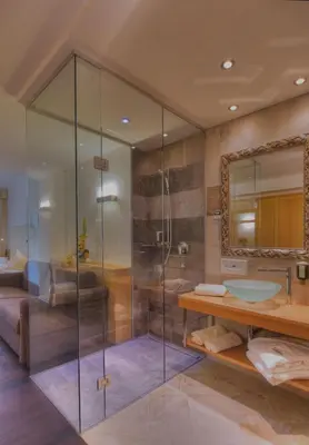 a bathroom with a glass shower and a sink at Hotel Leitner in Mühlbach