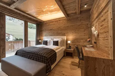 a bedroom with a bed and a desk and a window at Hotel Cappella in Colfosco
