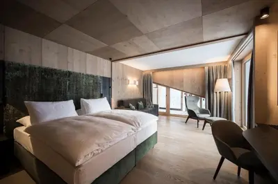 a bedroom with a large bed and a living room at Hotel Cappella in Colfosco